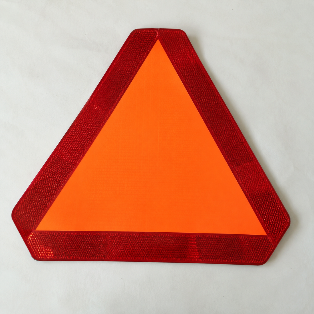 Fluorescent orange triangular emblem with a red border on a light surface.