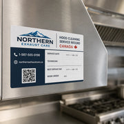 Custom hood cleaning service record sticker installed on a stainless steel commercial kitchen hood