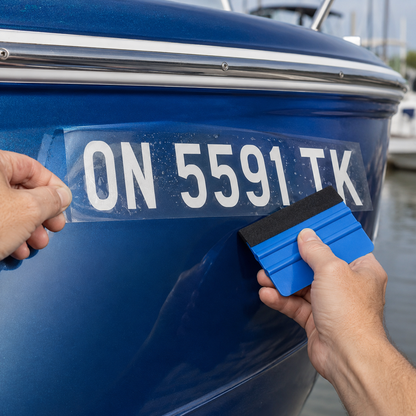 Illustrated close-up of transfer-tape application for a white boat number on a blue fibreglass bow