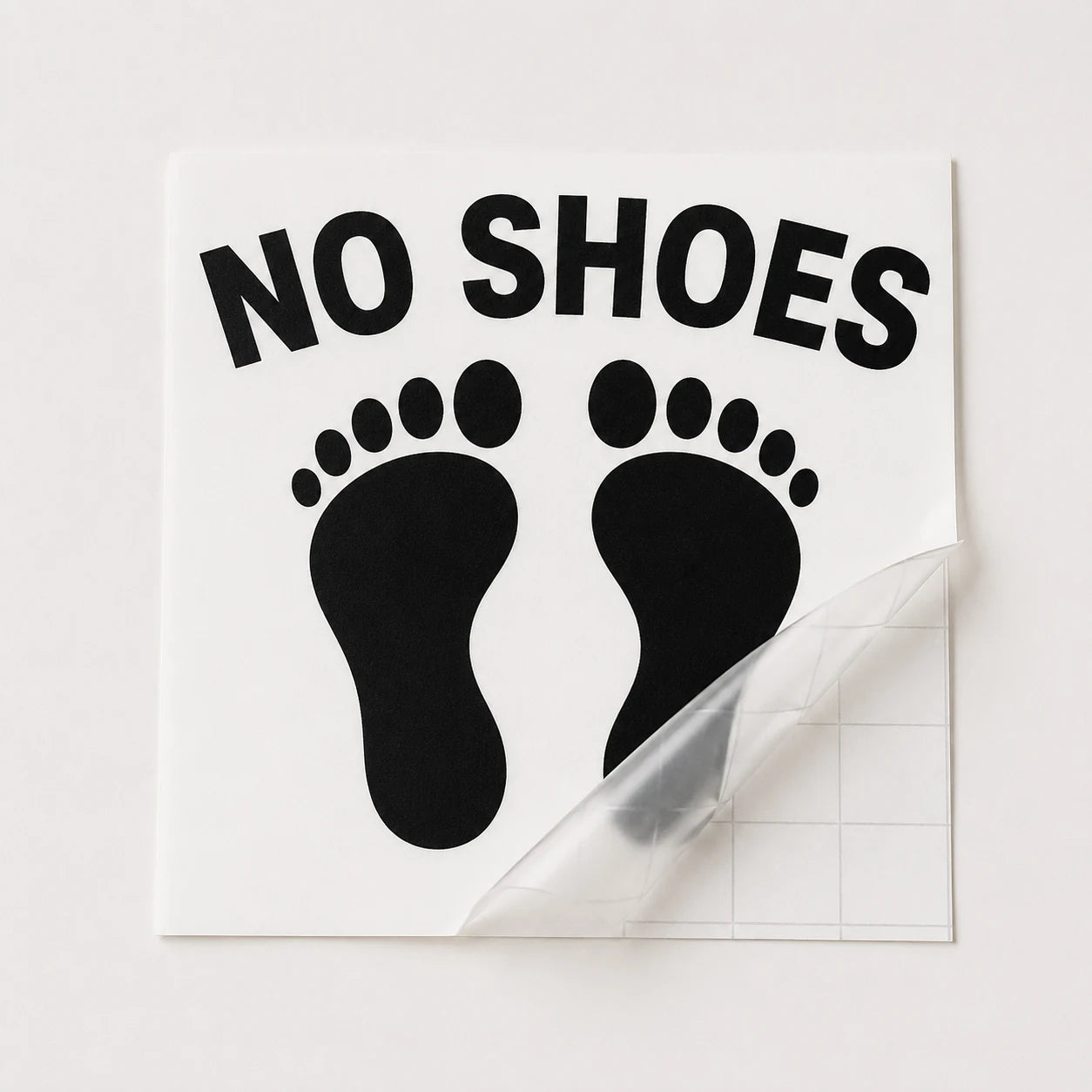Black No Shoes footprint boat decal shown under clear transfer tape before installation