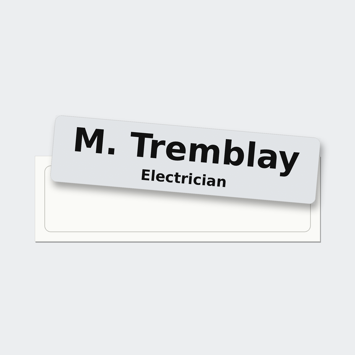 A 5 by 1.25 inch reflective hard hat name sticker reading M. Tremblay, Electrician, just peeled off its liner.