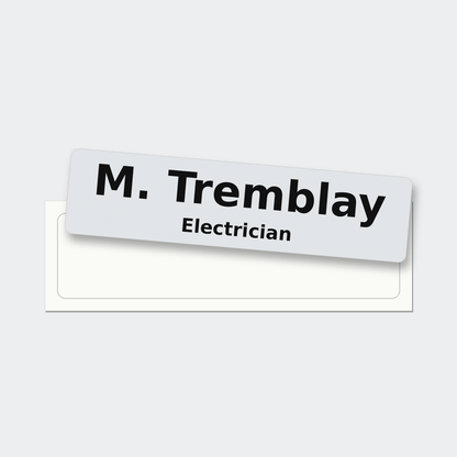 A 5 by 1.25 inch reflective hard hat name sticker reading M. Tremblay, Electrician, just peeled off its liner.