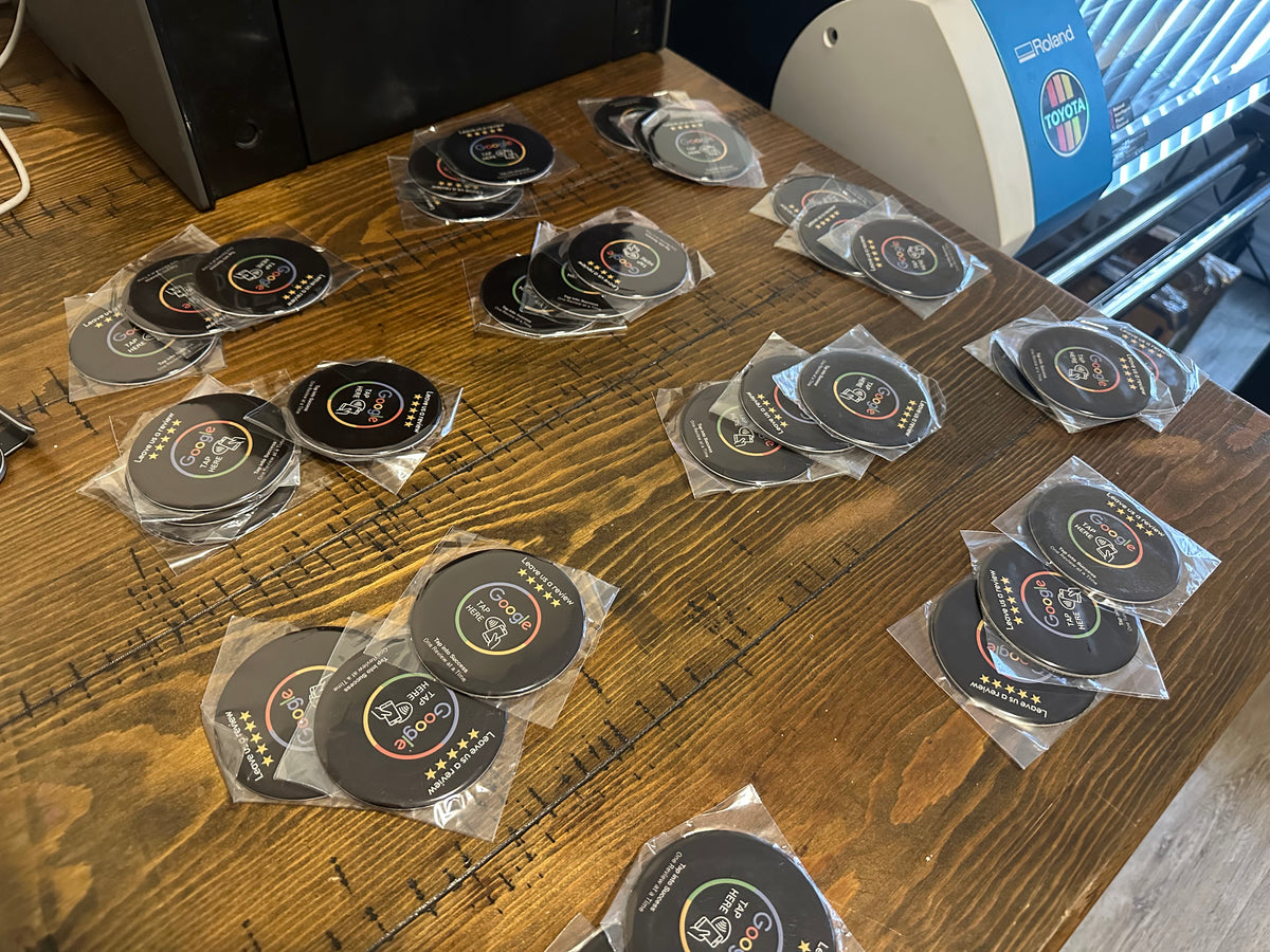 Stacks of NFC review cards with Google branding and five-star ratings are neatly arranged on a wooden table in an office setting.
