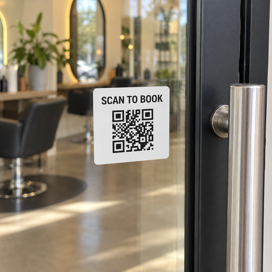A Scan to Book QR sticker beside a salon glass door handle.