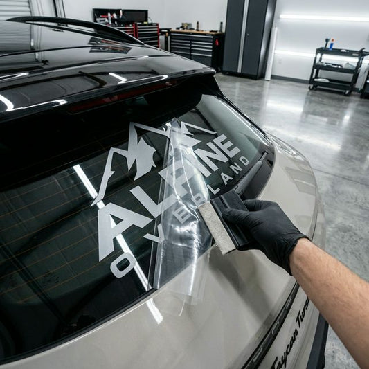 Vinyl decal transfer tape being squeegeed onto a clean vehicle surface