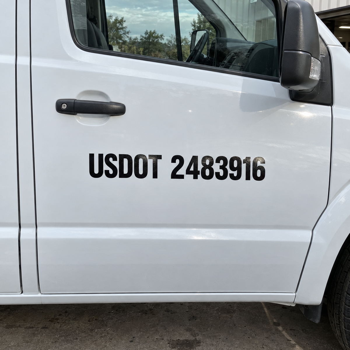 Black reflective USDOT 2483916 lettering sits clear of the handle and seam on a white work van’s passenger door.