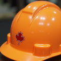 Orange hard hat with a round maple leaf vinyl sticker