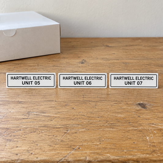Hartwell Electric equipment labels marked Unit 05, Unit 06 and Unit 07 on a bench.