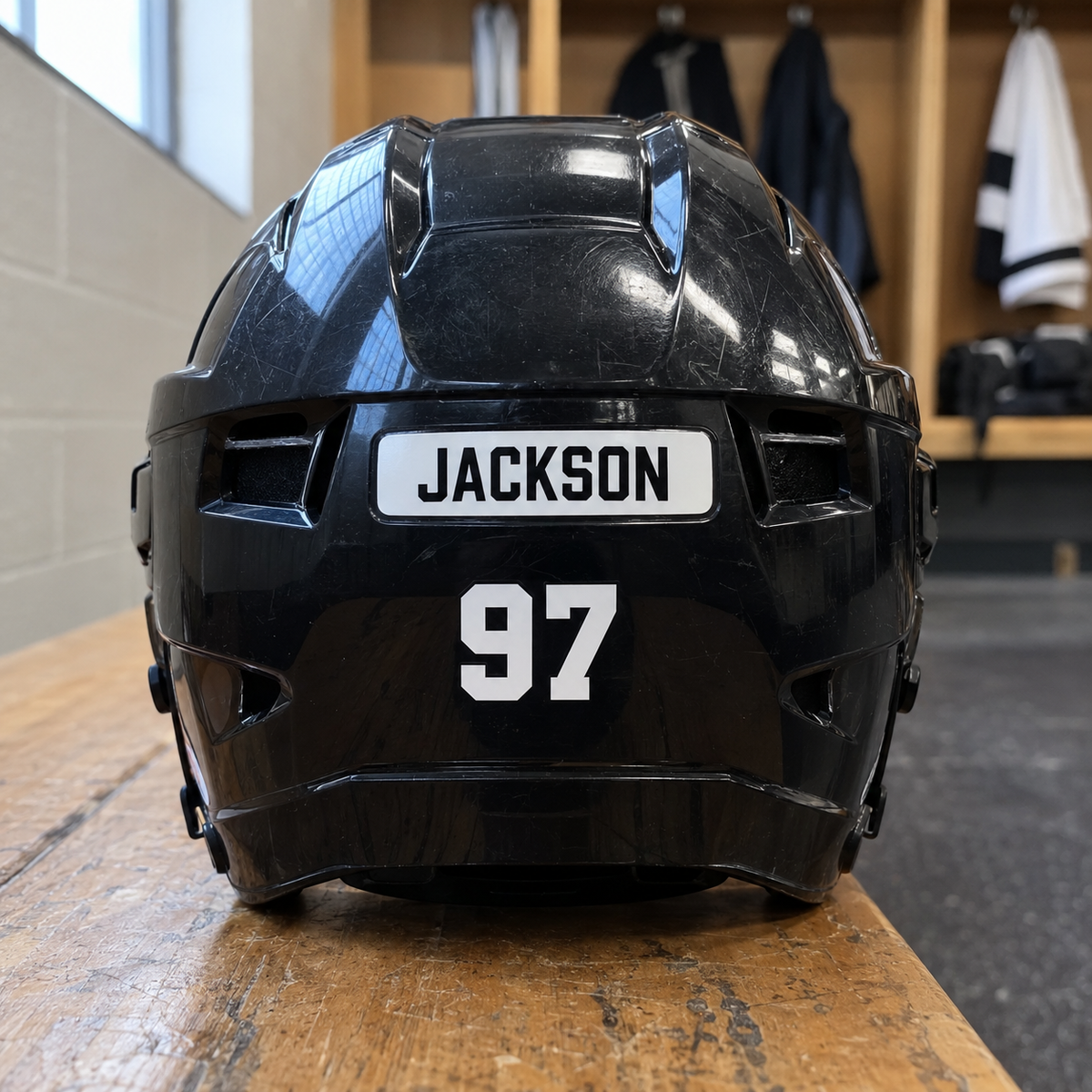 Jackson name sticker and number 97 on the back of a black hockey helmet.