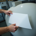 Hands positioning a blank rectangular vinyl label on a storage tank.