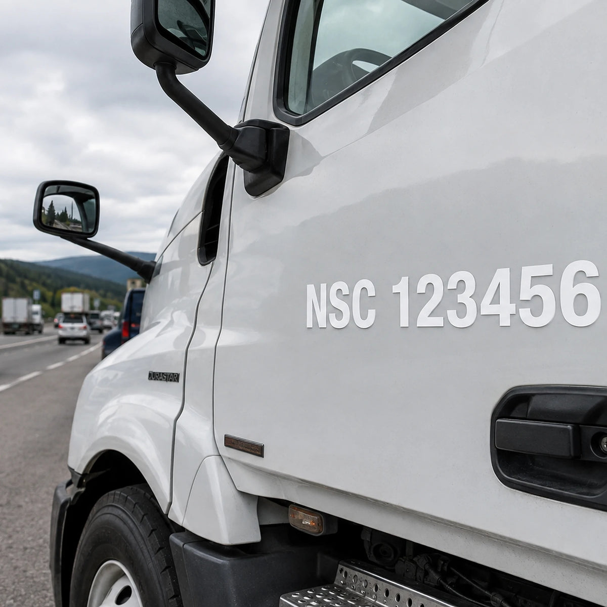 White NSC 123456 cut-vinyl safety-fitness number decal installed on a commercial truck cab door beside a Canadian highway.