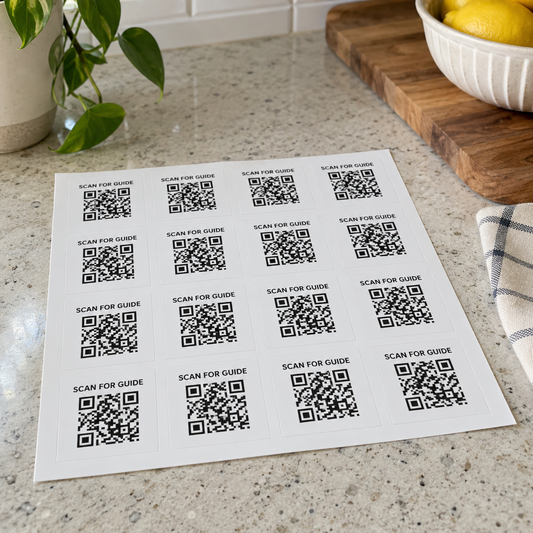 A sheet of square Scan for Guide QR labels on a kitchen worktop.
