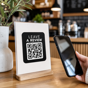 Customer scanning leave-a-review QR sticker at cafe counter